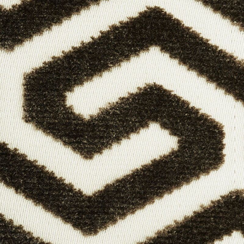 Close-up of a cream rug with a bold black geometric chevron/maze pattern in plush texture.