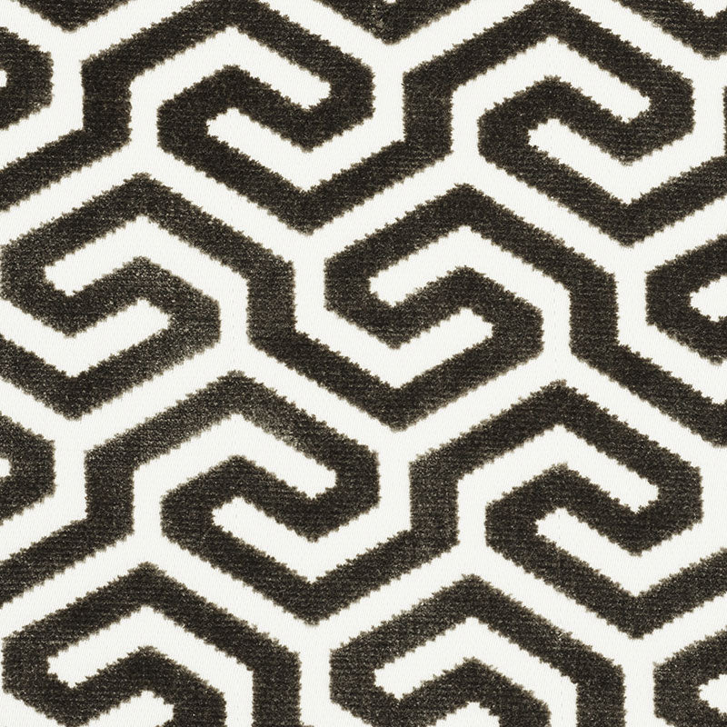 Black and white Greek-key geometric pattern on textured fabric.
