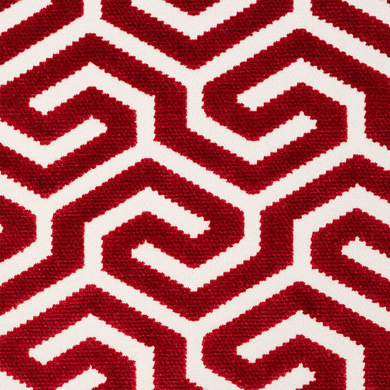 Close-up of red textured rug with interlocking Greek-key maze motifs on white background