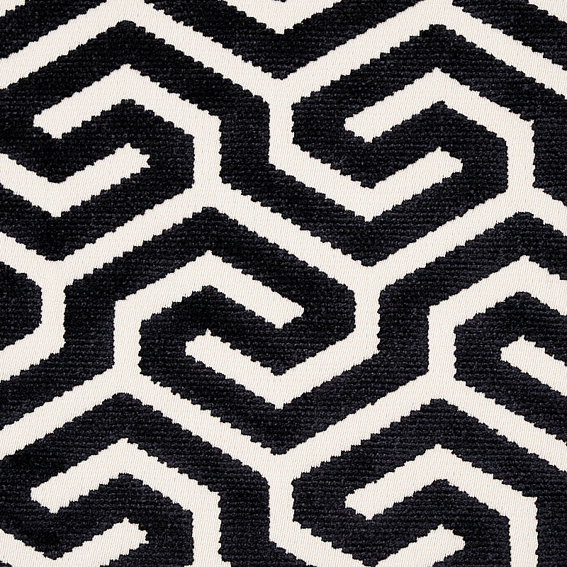 Black and white geometric maze pattern fabric with interlocking zigzag shapes; modern woven textile for upholstery or rug.
