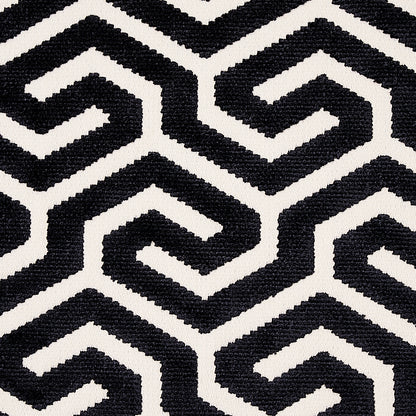 Black and white geometric maze pattern fabric with interlocking zigzag shapes; modern woven textile for upholstery or rug.