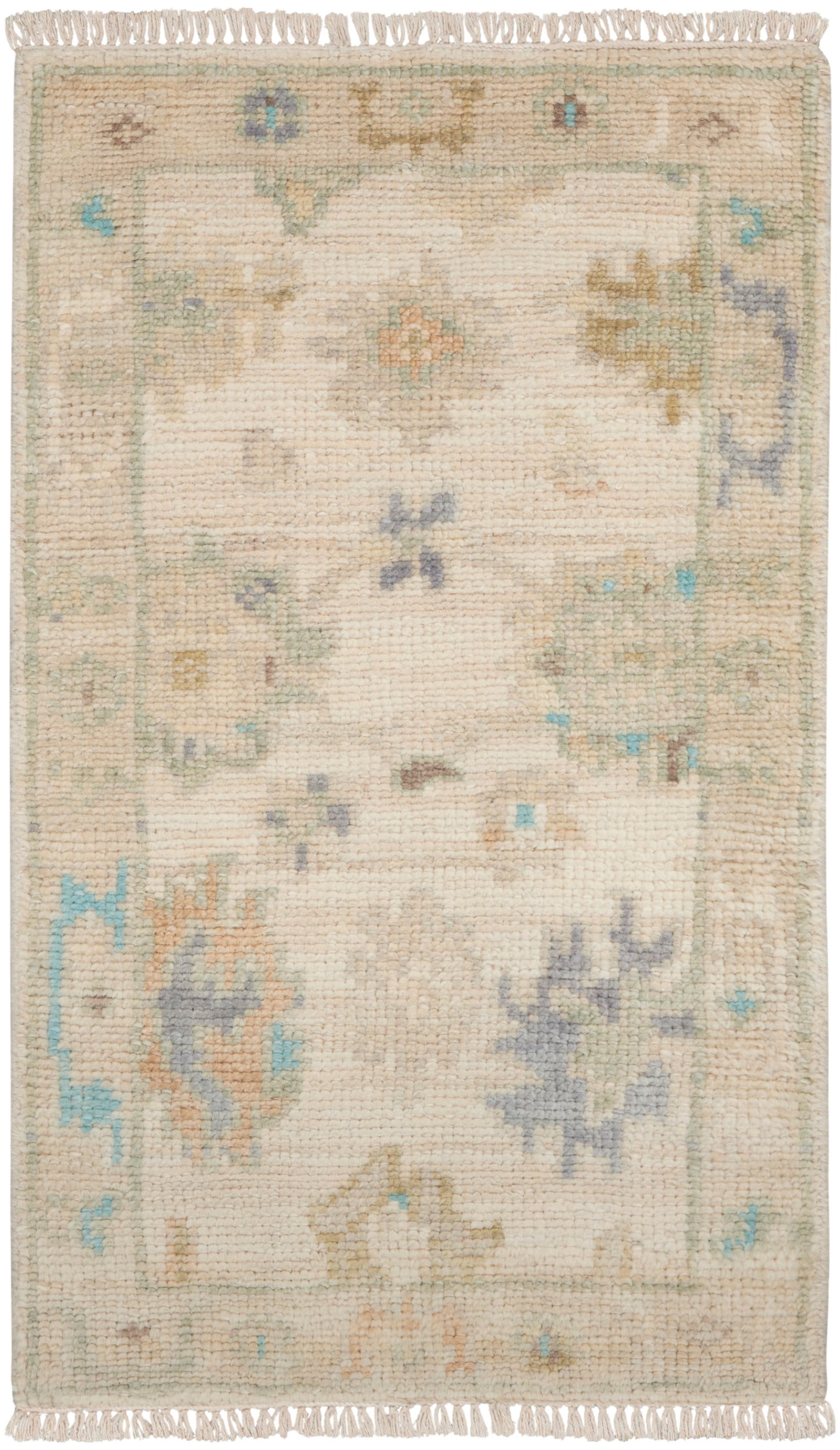 Rectangular beige handwoven rug with pastel floral motifs in sage, blue & peach; fringed ends.