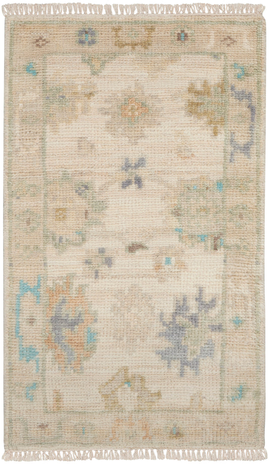 Rectangular beige handwoven rug with pastel floral motifs in sage, blue & peach; fringed ends.