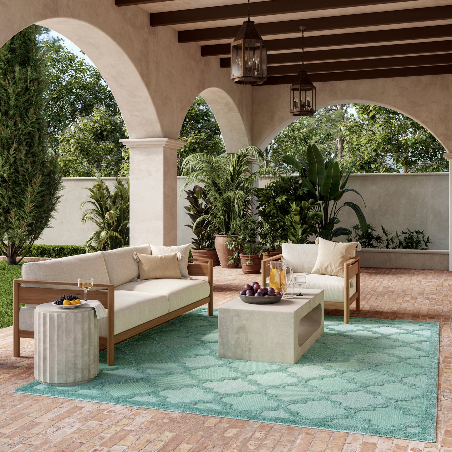 Outdoor patio with arched columns, beige cushioned wooden sofas, turquoise rug, concrete block coffee table, tropical plants, hanging lanterns.