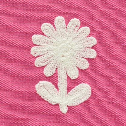 White embroidered daisy with stem and two leaves on pink textured fabric.