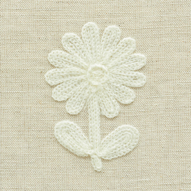 White crocheted daisy patch with stem and leaf on beige linen fabric.