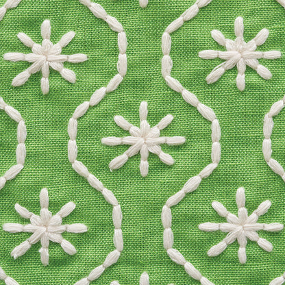 Green fabric with white embroidered chain-loop motifs and starburst flowers.
