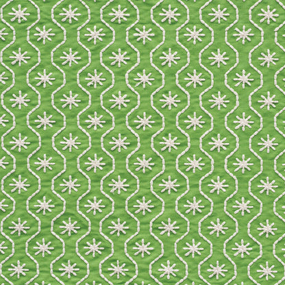 Green fabric with white embroidered interlocking loop trellis and starburst motifs.