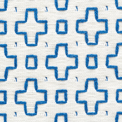 White fabric with repeating blue cross motifs and tiny square accents; textured embroidered pattern.