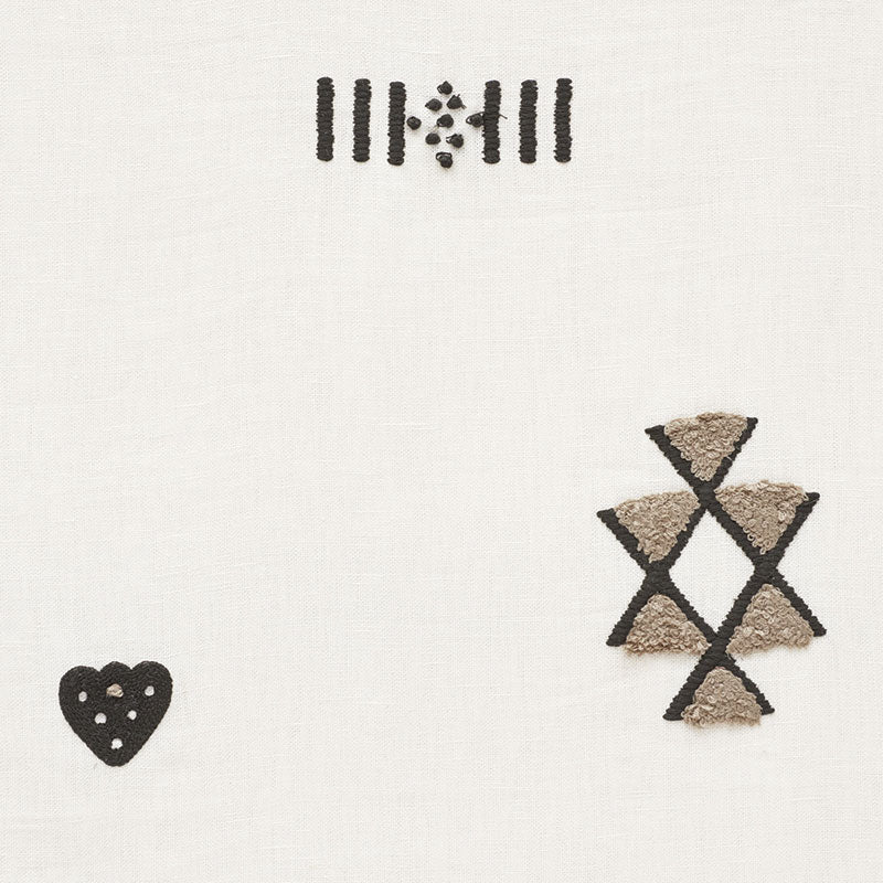 Cream sheer curtain with black geometric embroidery: top row of vertical bars, left black heart with cutouts, right stack of beige triangles outlined in black.