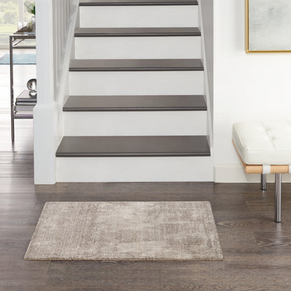 White staircase with dark wood treads, beige rug, modern white bench, framed art in a contemporary entry hall.