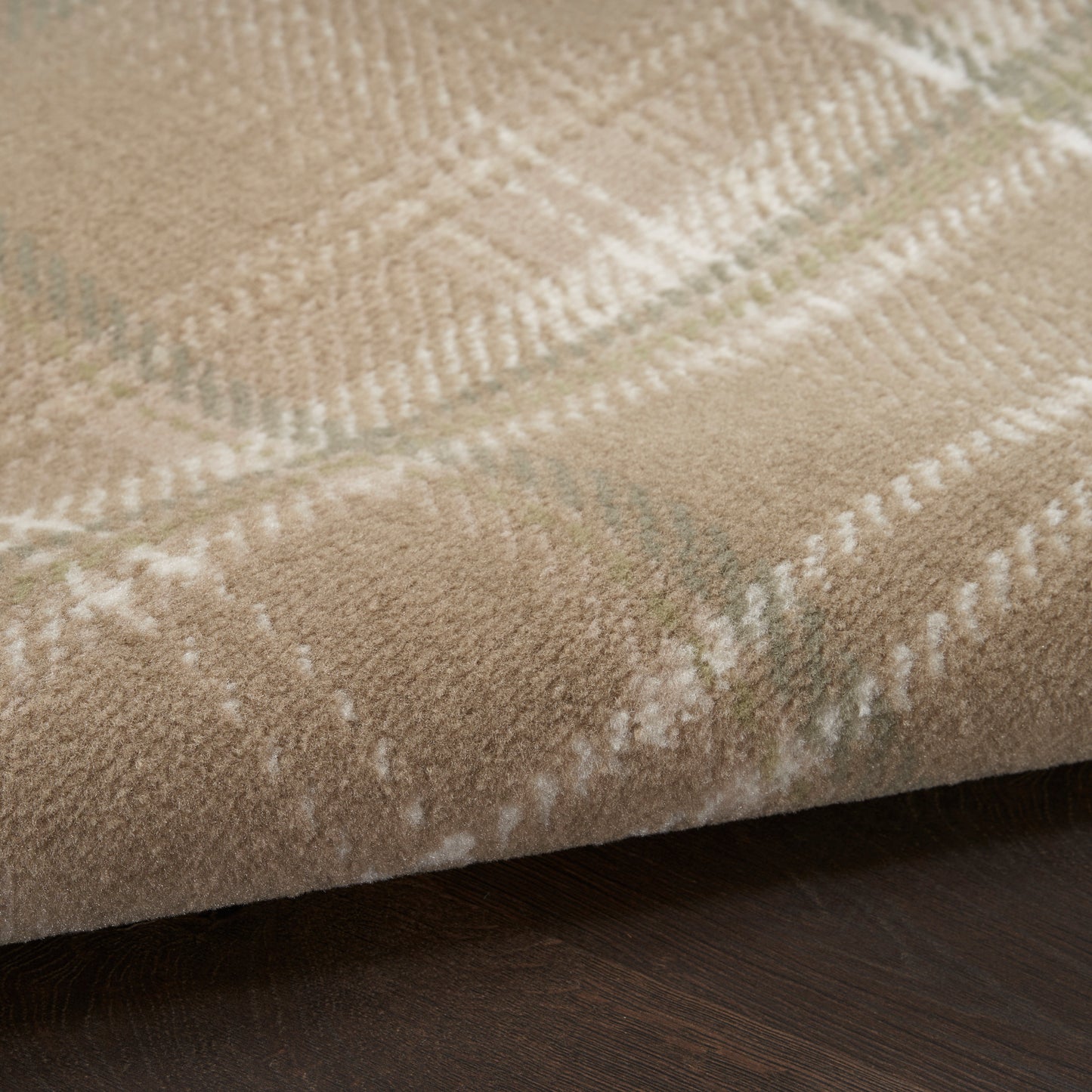 Beige plaid rug with white and pale green lines, soft textured pile on dark wood floor.