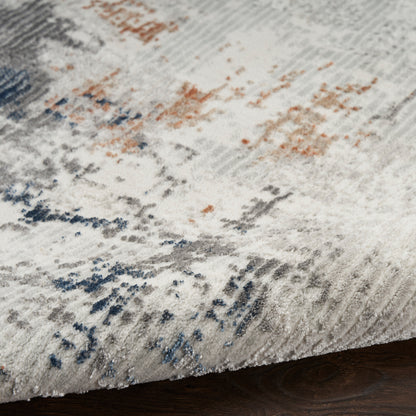 Abstract patterned rug with a light gray base, blue & rust accents, and a soft plush pile on dark wood floor.