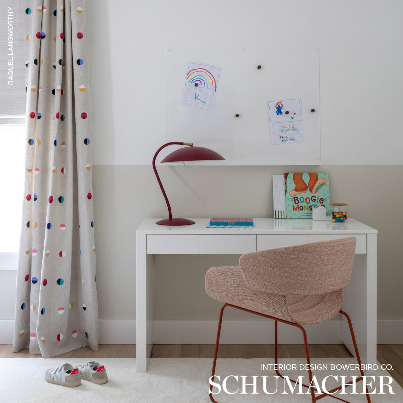 White desk with red arc lamp, pink upholstered chair, colorful polka-dot curtain, kid-friendly study nook.