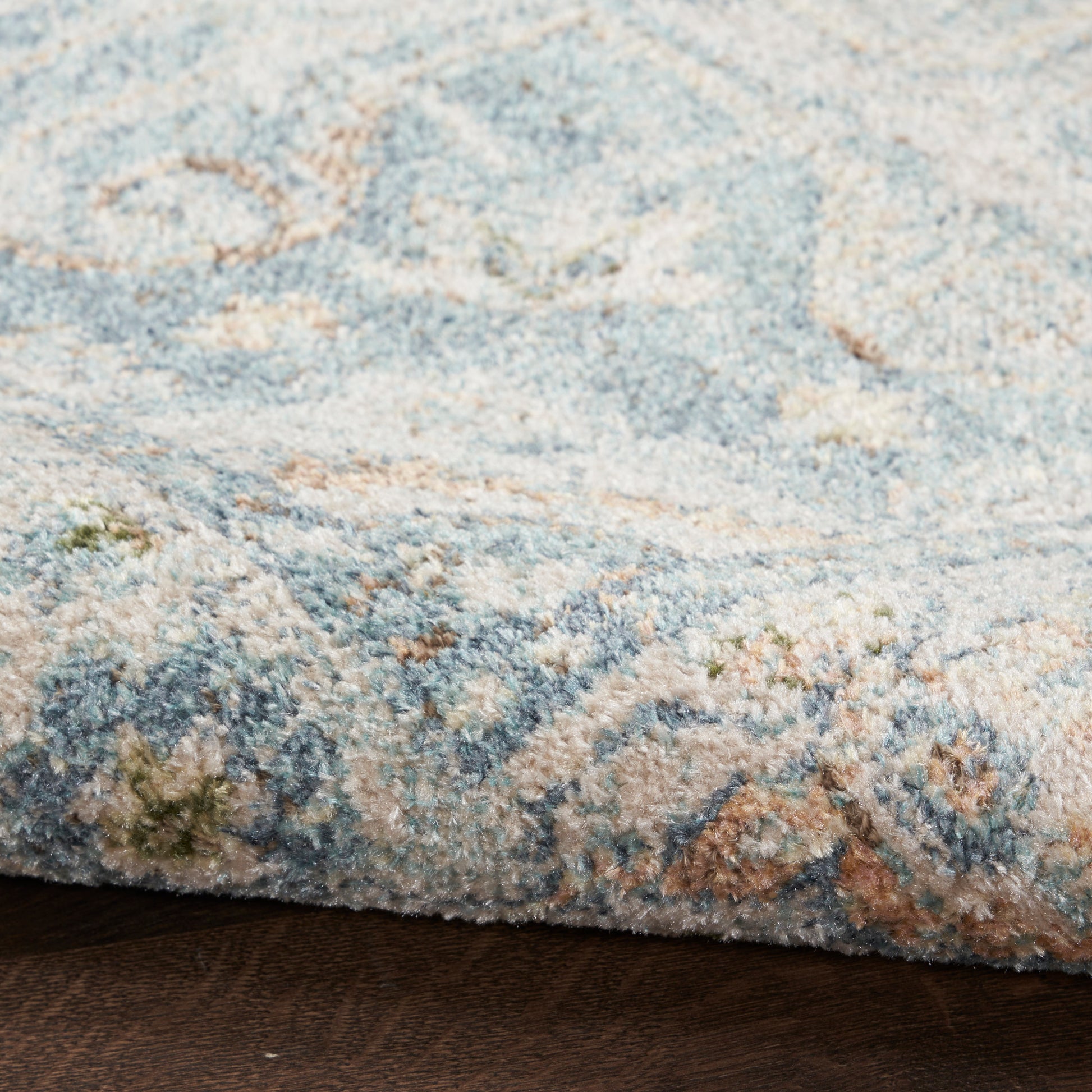 Close-up of a blue & beige patterned rug with light turquoise accents, thick plush pile & folded edge.