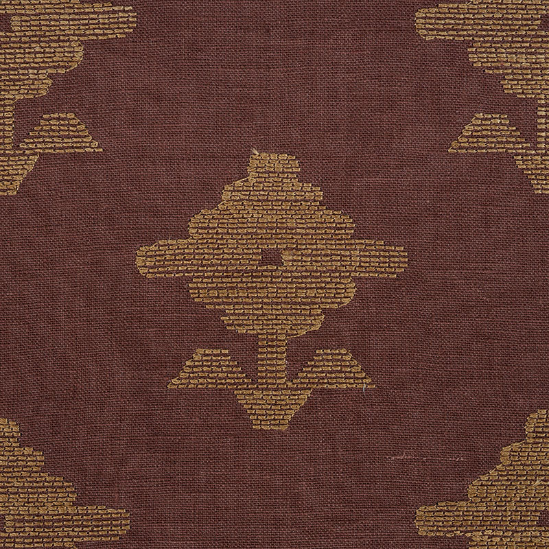 Brown embroidered textile with gold geometric medallion motifs in a kilim-style pattern.