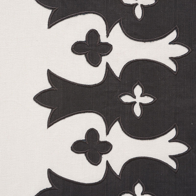 Cream fabric with bold black fleur-de-lis embroidery motifs in a vertical repeating pattern; high-contrast upholstery textile.
