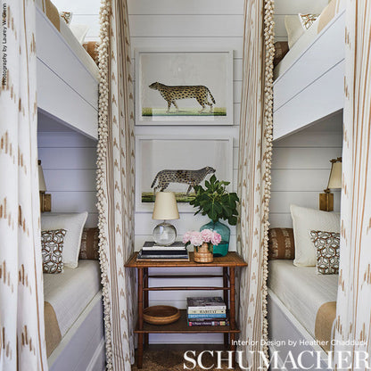 Cozy bunk room with white paneled walls, two bunk beds, leopard art, and a wooden console table with lamp, plant, and books.