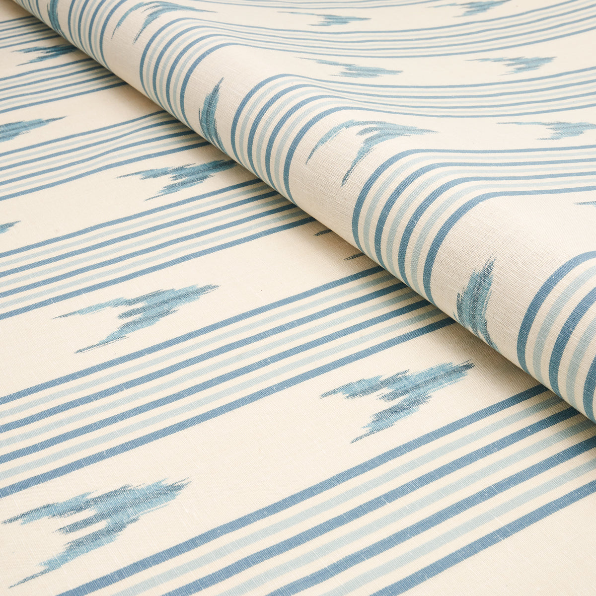 Cream fabric with blue ikat-inspired stripes, rolled edge; lightweight woven textile for curtains or upholstery.