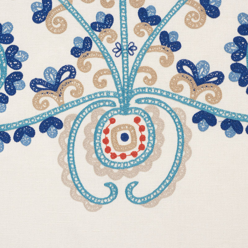 Embroidery-inspired floral pattern in turquoise & beige with blue blossoms on cream fabric, red bead accents.