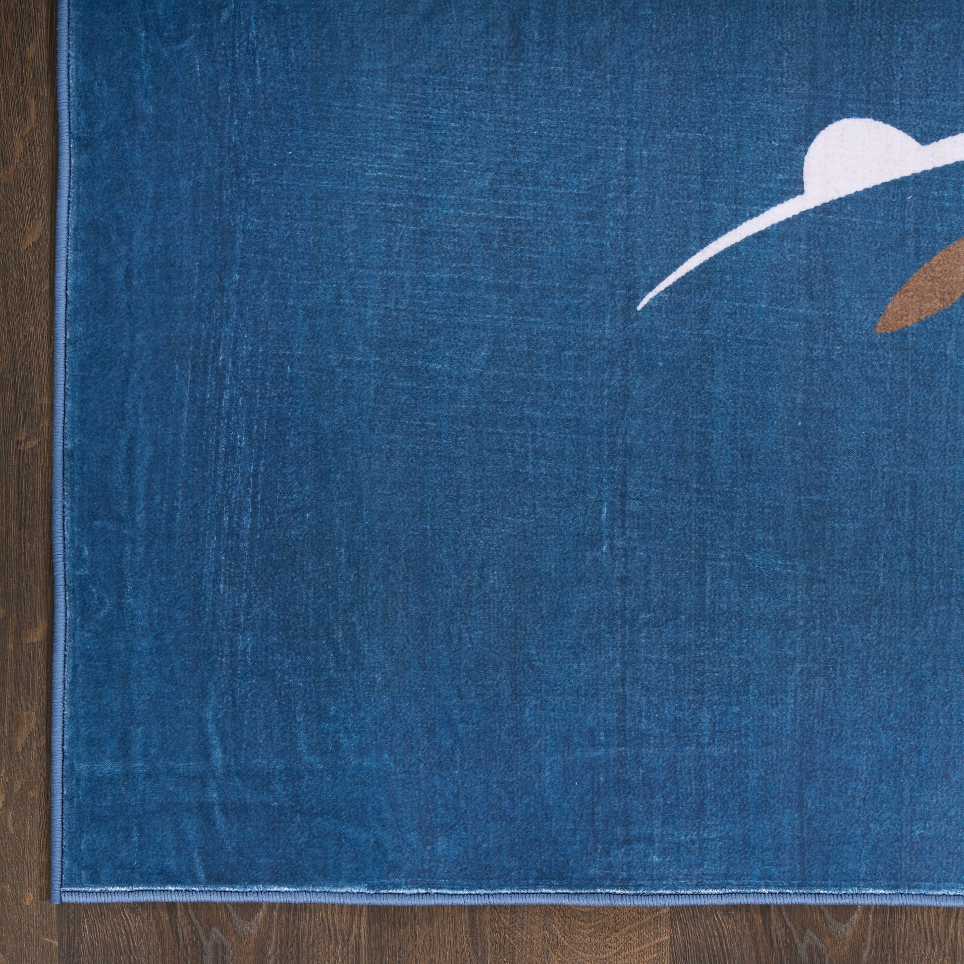 Blue textured rug with abstract white arc and brown accent on a wooden floor.