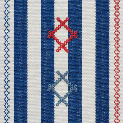 Woven textile with navy blue and white vertical stripes, red and pale blue diamond knot motifs, bordered by zigzag trims.
