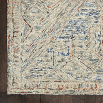 Cream and pale blue geometric area rug with diamond motifs and rust accents, bordered on dark wood floor.