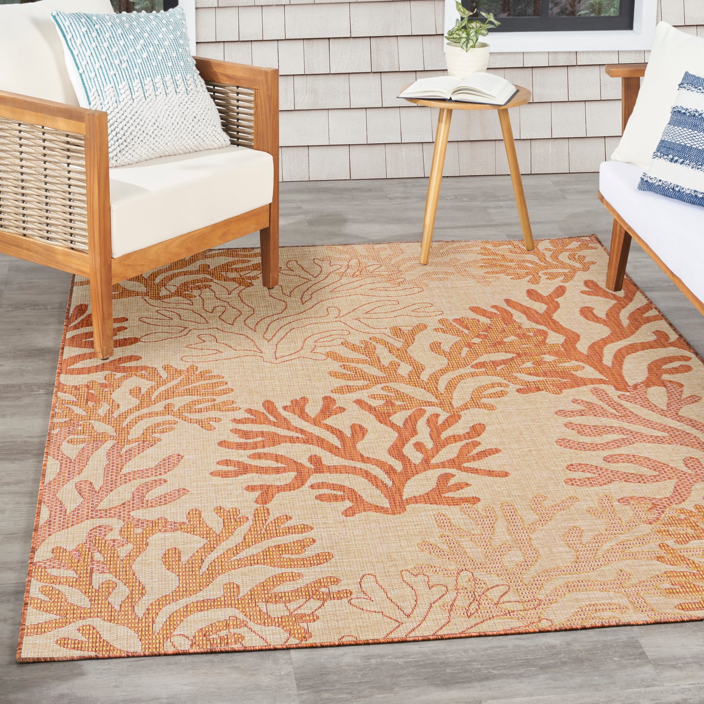 Rectangular beige outdoor rug with orange coral reef pattern; woven texture for patio seating.