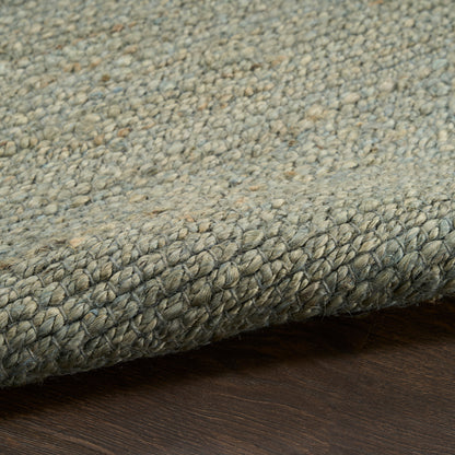 Blue-gray textured loop-pile rug edge with tight binding on dark wood floor.