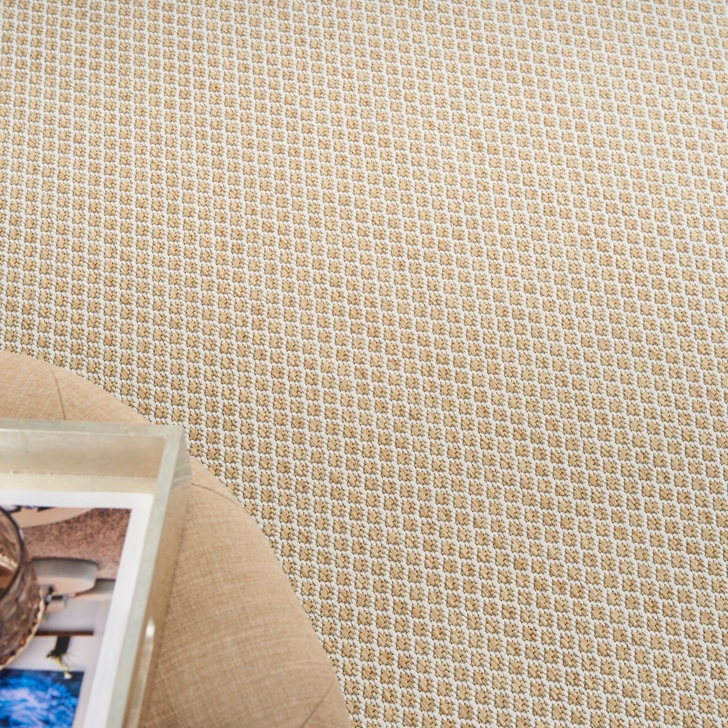 Beige woven rug with a small checkered pattern on the floor; round light-wood side table with magazines.