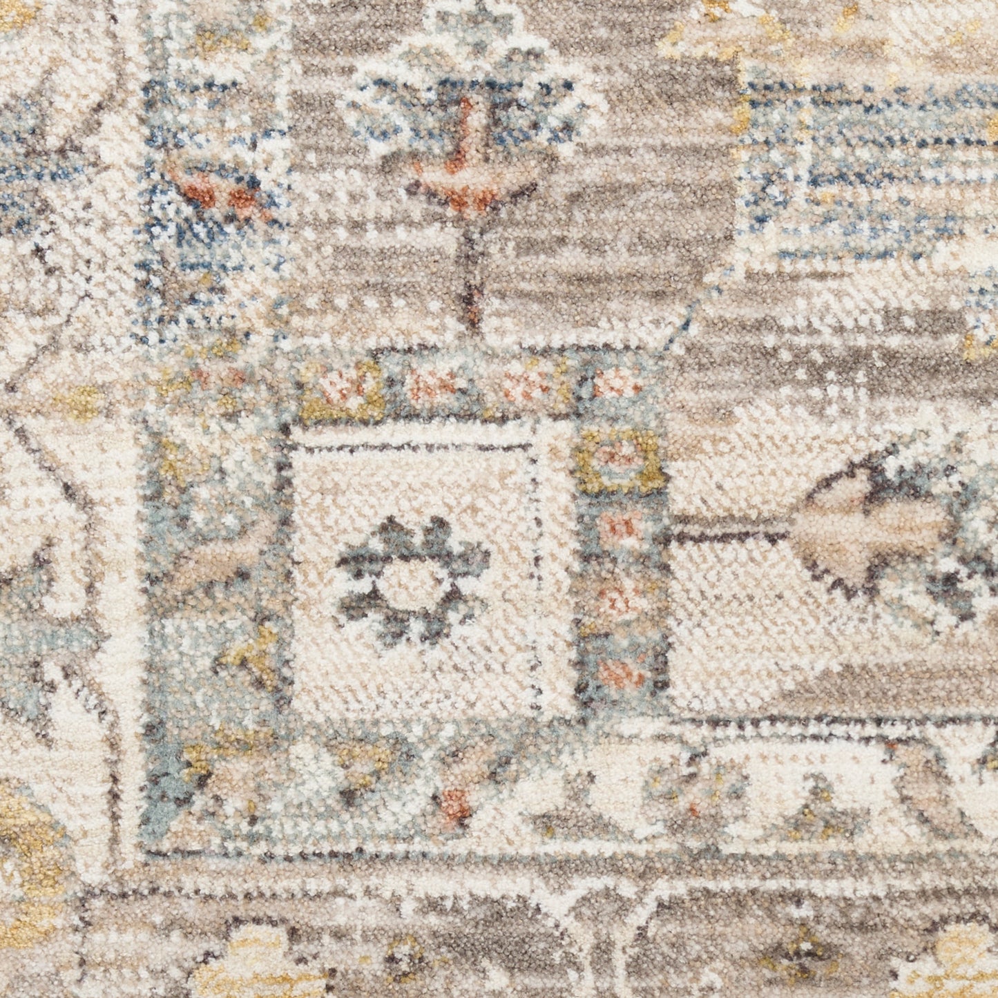 Close-up of a plush oriental rug with cream, taupe, blue and yellow geometric motifs.