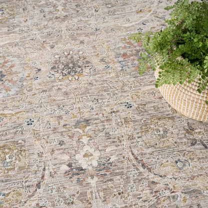 Beige vintage-style rug with a faded floral medallion pattern and subtle blue accents, on a floor beside a woven basket plant
