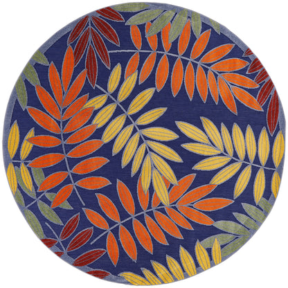 Round rug with navy blue base and vibrant orange, yellow, and green botanical leaf pattern.