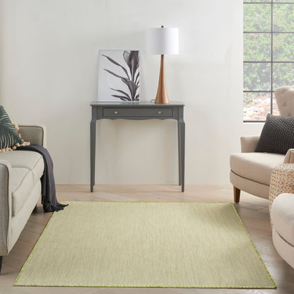 Gray console table with curved legs, two drawers, botanical art, wooden-base lamp, beige seating on a pale green rug.