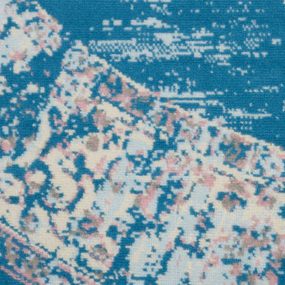 Close-up of a blue rug with cream-pink floral pattern and distressed texture.