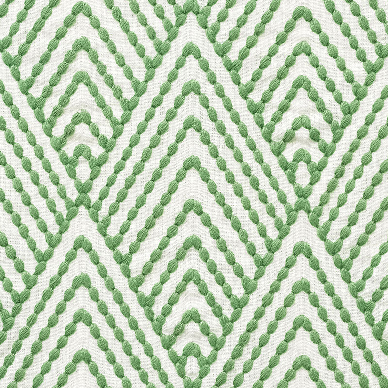 Close-up of white fabric featuring a green braided rope chevron pattern.