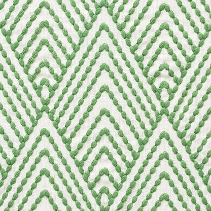 Close-up of white fabric featuring a green braided rope chevron pattern.