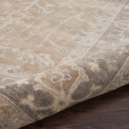 Beige distressed oriental rug with cream floral motifs and rolled edge on dark wood floor