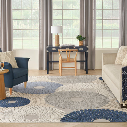 Cozy living room with navy desk, light wood chair, gray sofa, blue armchair, circular gray-blue rug, open book.