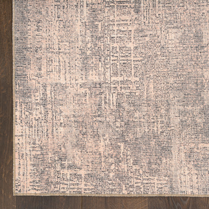 Rectangular area rug with soft textured pile, abstract distressed pattern in gray-blue on beige, on dark wood floor.