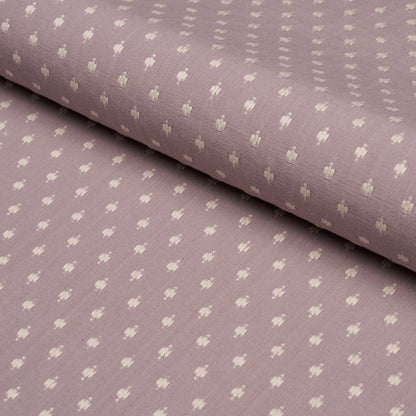 Rolled lavender fabric with tiny white floral motifs in a soft cotton-like weave.