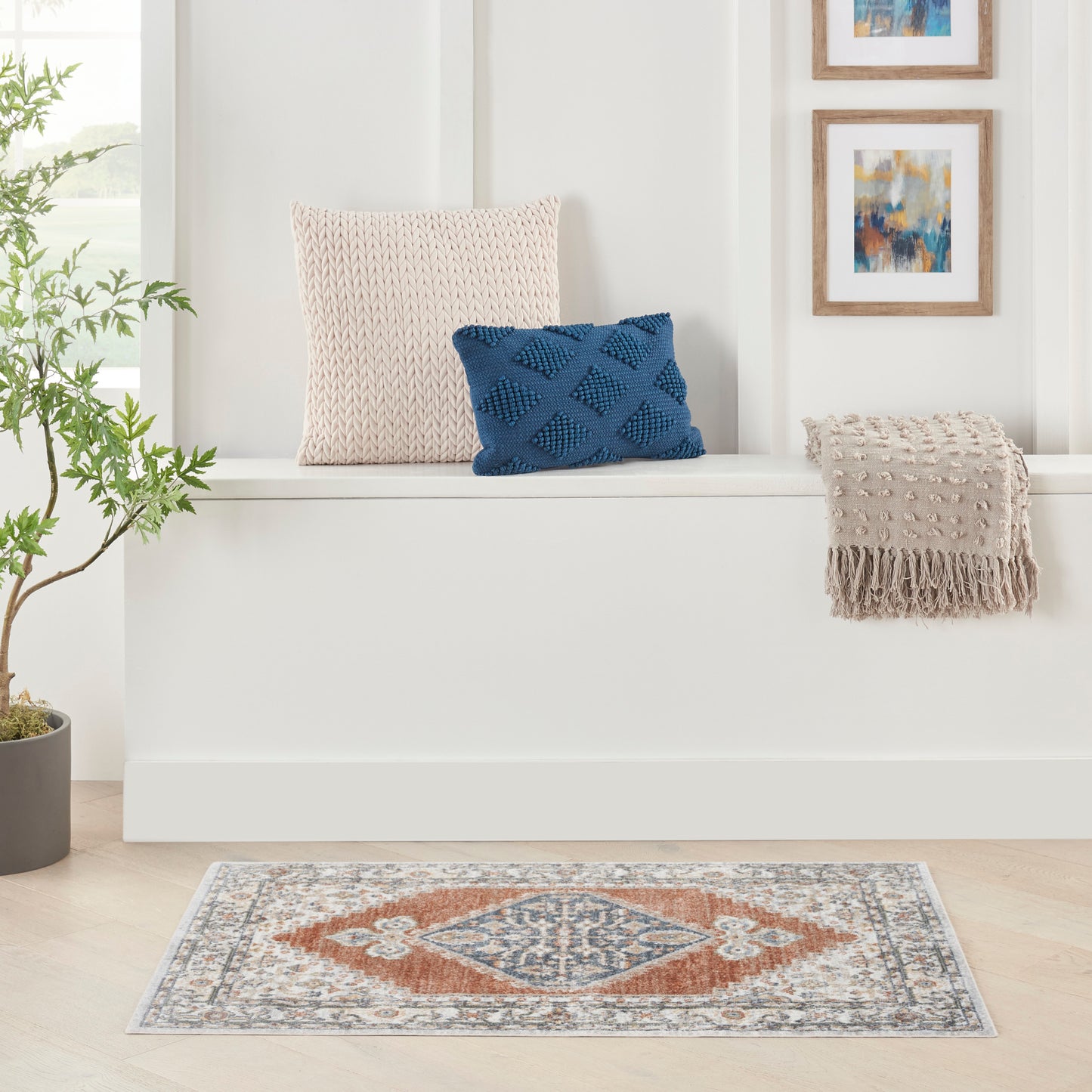 Cream vintage rug with a geometric pattern; room scene featuring a plant and framed art.
