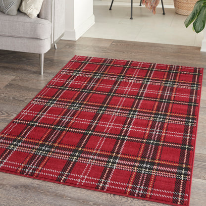 Red plaid area rug with black and white accents on dark wood floor in a cozy living room.