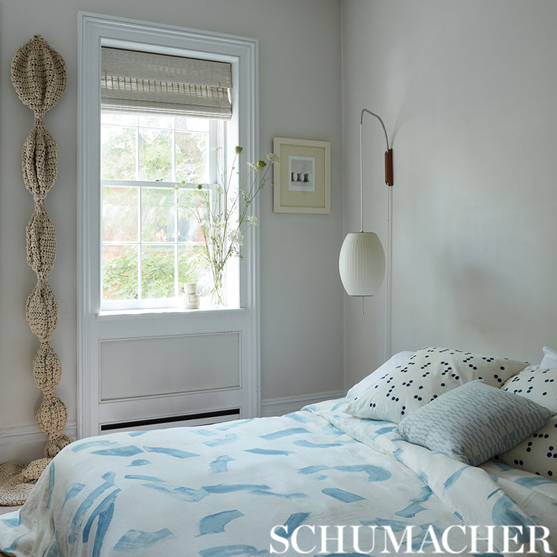 Soft blue and white duvet with abstract shapes in a calm bedroom, white ribbed pendant lamp and woven rope decor by window.