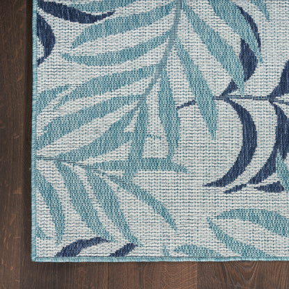 Teal and navy leaf-patterned woven rug on dark wood floor, light background, turquoise edge binding.