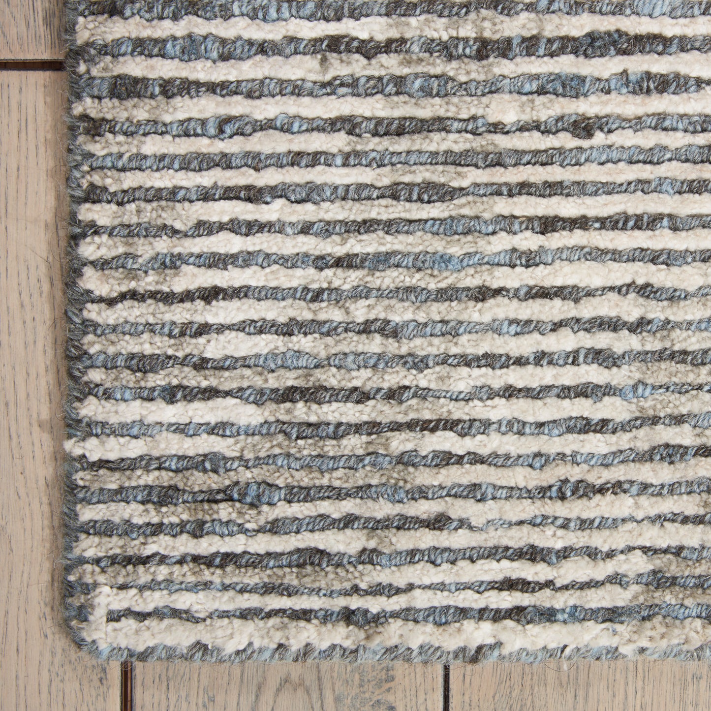 Cream and gray striped boucle rug with textured loops on light wood floor.
