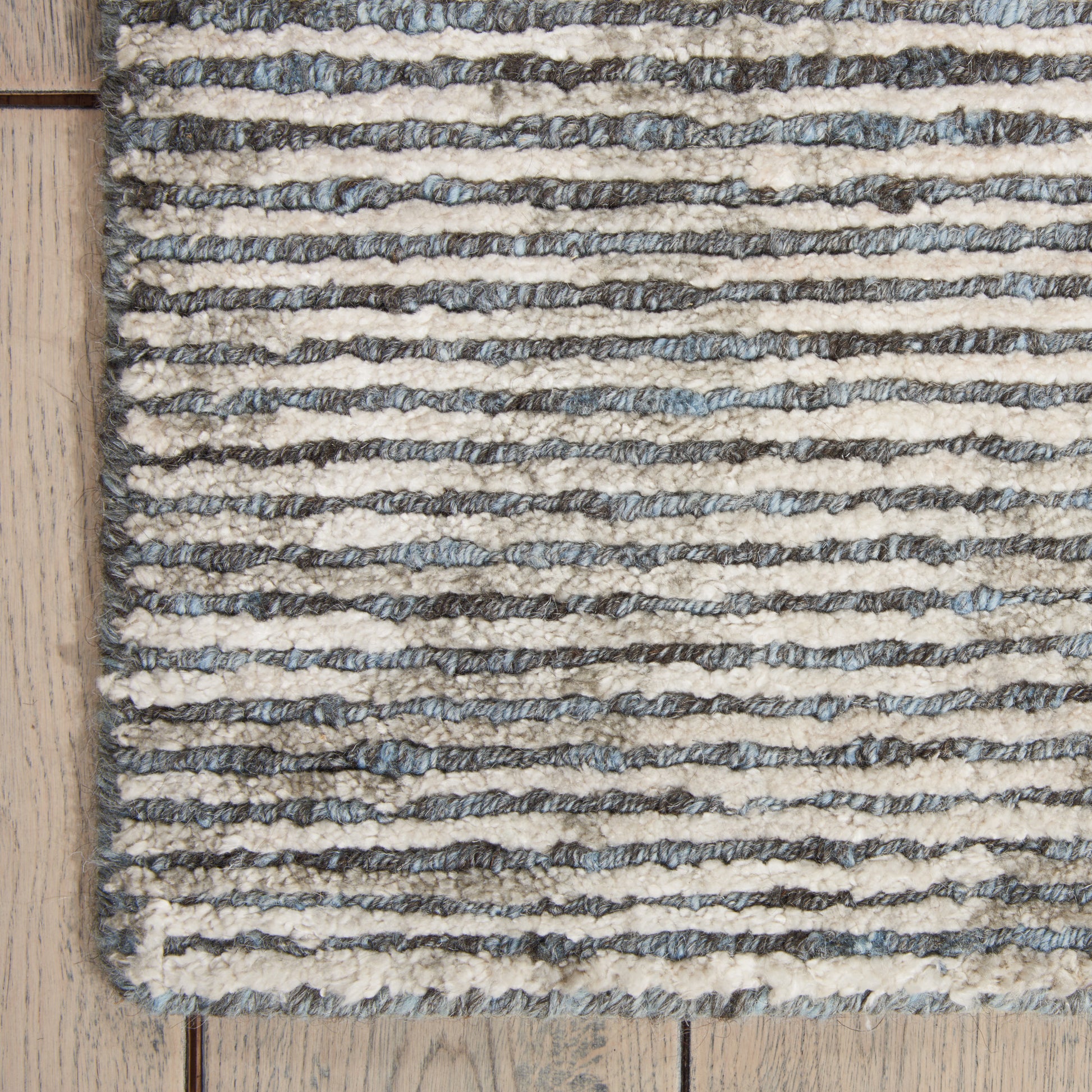 Cream and gray striped boucle rug with textured loops on light wood floor.
