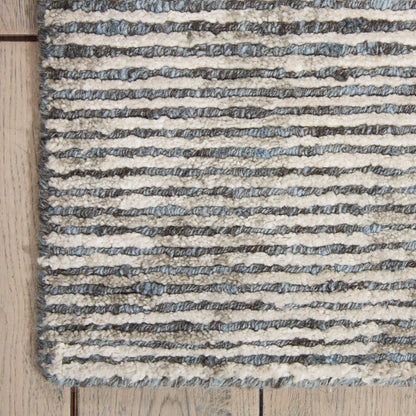 Cream and gray striped boucle rug with textured loops on light wood floor.