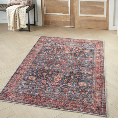 Persian-style Oriental rug with navy blue field, red floral medallions, and layered red/ivory borders on light wood floor.