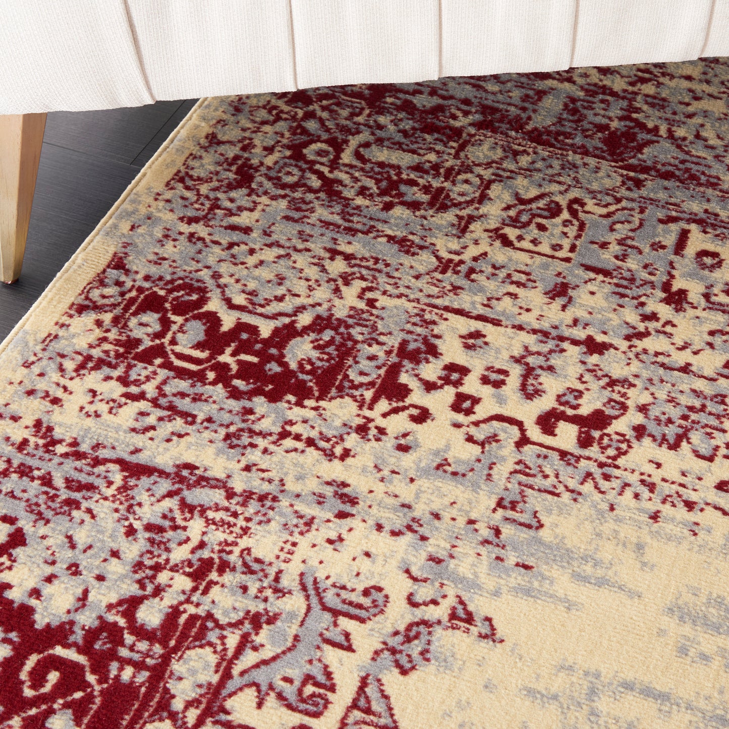 Beige oriental rug with burgundy floral medallion pattern, distressed blue-gray accents, low-pile under a light sofa.
